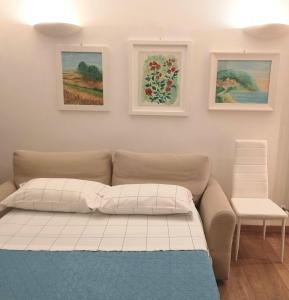 un divano in una stanza con tre quadri alle pareti di Giardino delle rose a Lido di Fermo