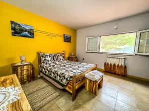 1 dormitorio con paredes amarillas, 1 cama y ventana en Lugar dos Vales-Memorável, Encantador e Autêntico!, en Mirandela