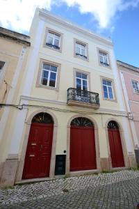 a white building with red doors and a balcony at Sport Hostel Figueira da Foz in Figueira da Foz