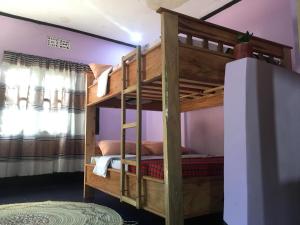 a bunk bed in a room with purple walls at Ava garden backpackers in Mto wa Mbu