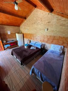 a bedroom with two beds and a brick wall at Chalés Pedacim du Céu in Bueno Brandão