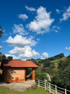 布埃諾布蘭的住宿－Chalés Pedacim du Céu，白色的栅栏和蓝色的天空的砖砌建筑