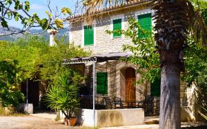 una antigua casa de piedra con persianas verdes en Finca Son Jordà, en Campanet