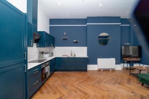 cocina con armarios azules y suelo de madera en 1ST MORDEN STUDIO FLAT Moments away from Brighton seafront, en Brighton & Hove