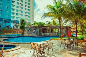 a pool with tables and chairs and a building at Ecologic Ville Resort - Oficial in Caldas Novas