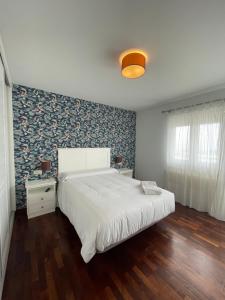 Un dormitorio con una gran cama blanca y una pared en Hostal Portofino, en Portosín