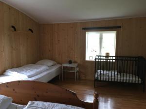 a bedroom with two beds and a window and a crib at Fråsttorp in Aneby