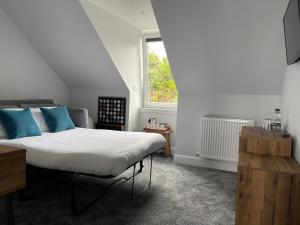 Un dormitorio con una cama con almohadas azules y una ventana en Killorn Guest House, en Oban