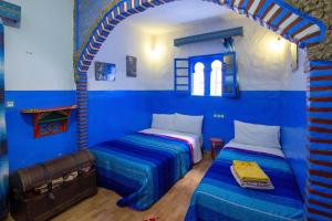 two beds in a room with blue walls at Casa La Hiba in Chefchaouen