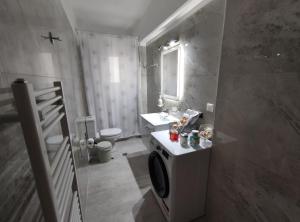 a bathroom with a sink and a washing machine at Grey Swan - Modern & Stylish apartment with Private Parking in Volos