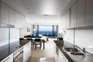 cocina con armarios blancos y vistas al océano en Mantra Sierra Grand, en Gold Coast