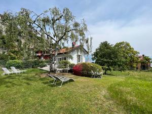 a house with two white benches in the grass at Le Betulle in Oggebbio