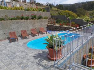 un patio con piscina, sillas y plantas en Banda Do Sol Self Catering Cottages, en Estreito da Calheta