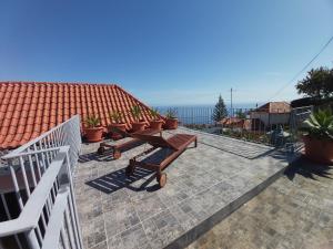 a patio with tables and benches on a roof at Banda Do Sol Self Catering Cottages in Estreito da Calheta