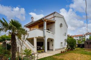 a white house with a palm tree in the yard at Apartment Anton in Punat