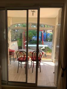 una puerta de cristal que da a un patio con mesa y sillas en Appartement jardin Cap d'Agde en Cap d'Agde