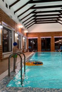 a man in a swimming pool with a surfboard in it at Приватний будинок для сімейного відпочинку з басейном і сауною in Grigorʼyevka