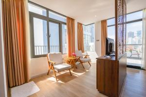 a living room with a table and chairs and windows at Simon Hotel in Nha Trang
