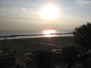 a view of a beach with the sun setting over the ocean at Hotel Rosati in Rimini