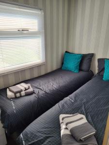 a bedroom with two beds with blue pillows and a window at Stylish holiday home with fishing lakes in Fiskerton
