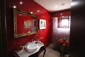 a red bathroom with a sink and a mirror at Quinta dos Padrinhos - Suites in the Heart of the Douro in Lamego +37 photos