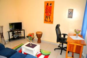 a living room with a blue couch and a tv at Victoria Lake View Guesthouse & Safaris in Entebbe