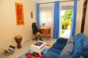 a living room with a blue couch and a desk at Victoria Lake View Guesthouse & Safaris in Entebbe