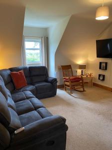 a living room with a blue couch and a chair at Racecourse Lodge Apartment in Clifden