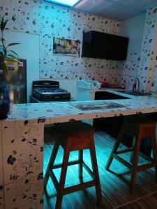 a kitchen with a counter and two bar stools at APARTA-Refugio El Retiro Verde in Leticia