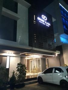a white car parked in front of a building at night at Grand Plaza Boutique Hotel in Karawang