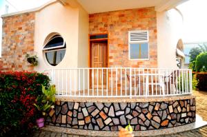 a house with a balcony with a stone fence at Victoria Lake View Guesthouse & Safaris in Entebbe