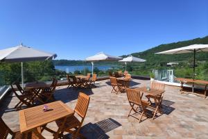 a patio with wooden tables and chairs and umbrellas at il Lago di Nemi in Nemi