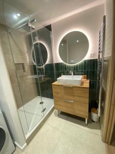 a bathroom with a shower and a sink and a mirror at Superbe appartement avec piscine in Carqueiranne