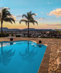 a swimming pool with palm trees and a city at Varandas da Montanha in Carmo do Rio Claro