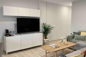 uma sala de estar com uma televisão de ecrã plano num armário branco em YELLOW SAIL MÉDANO 2 Dormtiorios con parking em El Médano