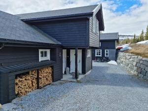 a black house with a garage and a stone wall at Fosskamben Panorama Sogndal in Sogndal