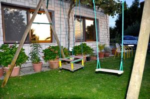 a yard with a swing and a bench in front of a house at Apartment in the heart of Brda wine region, Boris and Darinka Marinič in Dobrovo
