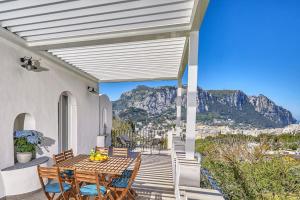 eine Terrasse mit Tisch und Stühlen und Bergen in der Unterkunft DENTECALA 4 in Capri