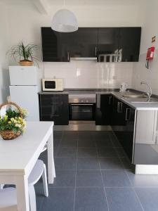 uma cozinha com armários pretos e uma mesa branca em Alojamento Justo - vila de Montargil em Montargil