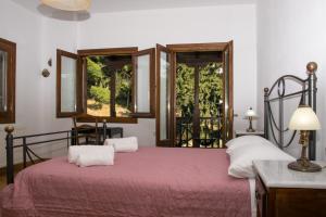 1 Schlafzimmer mit einem Bett mit einer roten Tagesdecke und 2 Fenstern in der Unterkunft Mountain Breeze Sanctuary in Volos