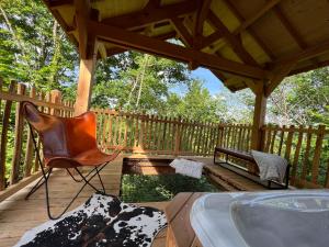 a wooden deck with a chair and a hot tub at Dôme à Bulles in Orcines