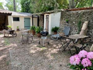 un patio trasero con parrilla, mesas y sillas en Mazet proche Golf, en Nimes