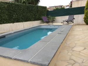 - une piscine avec deux chaises dans la cour dans l'établissement Villa L'Adret et sa piscine, à Juan-les-Pins