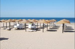 plaża z leżakami i parasolami oraz ocean w obiekcie Chipiona Apartamento Bajo Centro Parking Incluido WiFi GRATIS w mieście Chipiona