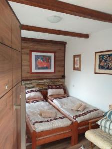 two twin beds in a room with wooden walls at Restaurant and Apartments - T'ga za Jug Lazaropole in Lazaropole