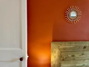 an orange wall with a mirror and a wooden box at Le Cosy in Bayeux