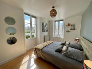 a bedroom with a large bed and two windows at Le Cosy in Bayeux