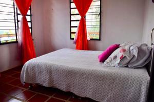 a bedroom with a bed with red curtains and two windows at Saranna Cabaña in San Agustín