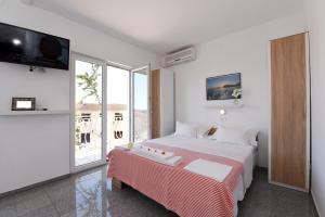 a white bedroom with a bed and a tv at Makarska sea view rooms in Makarska