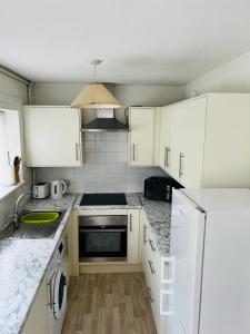 una cocina con armarios blancos y encimeras de mármol en semi-detach en Saint Helens